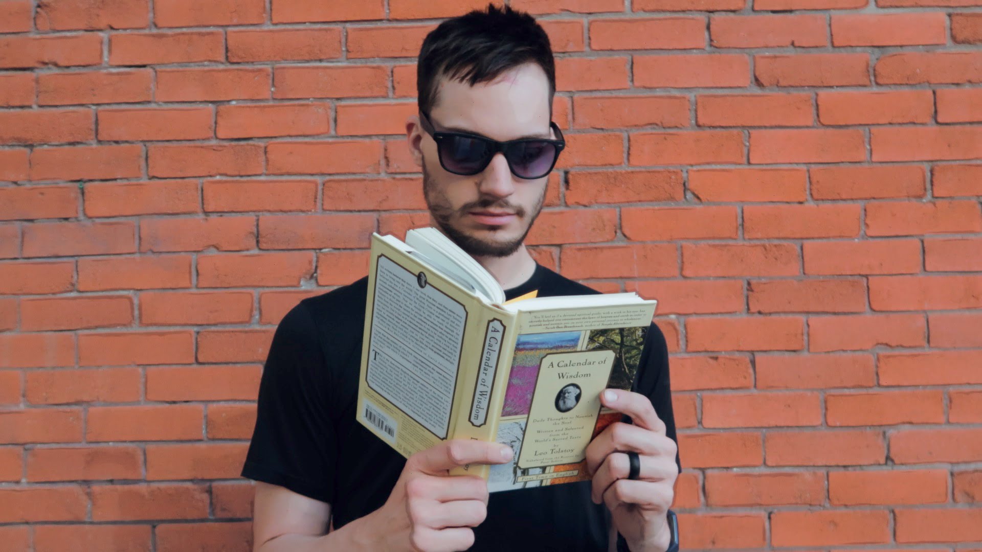 ScootyDub reading Tolstoy's Calendar of Wisdom in front of a brick wall