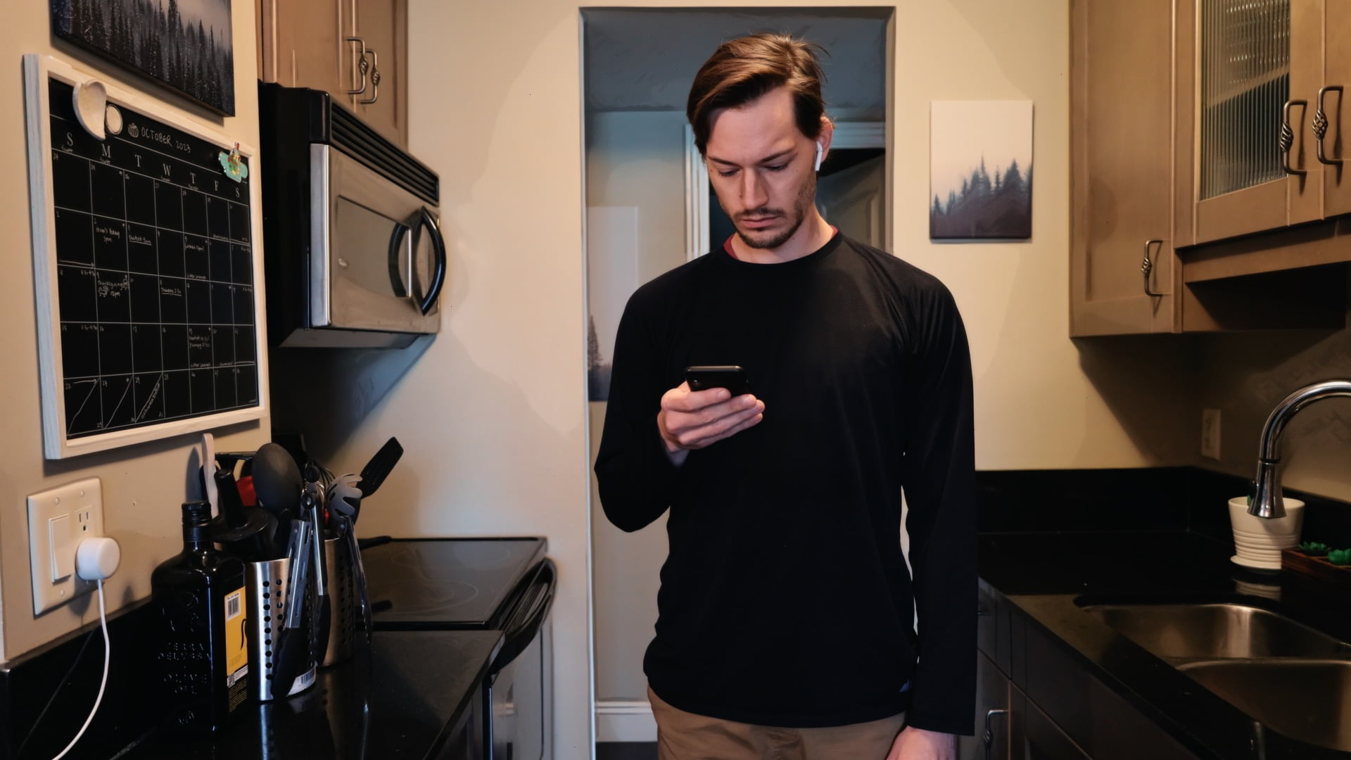 ScootyDub scrolling on his phone in the kitchen